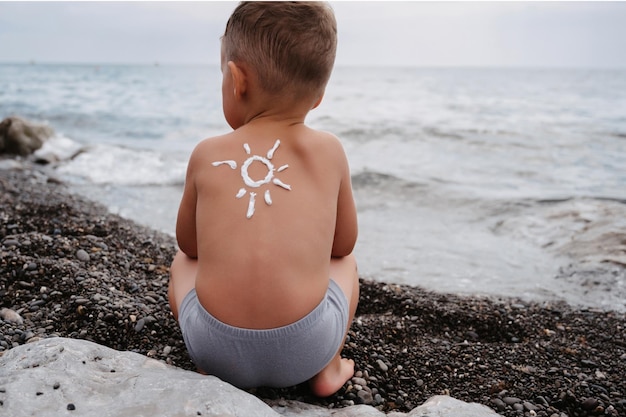 Nahaufnahme der Schulter eines Jungen mit einem Sonnenschutzmuster, das mit Sonnenschutzmittel hergestellt wurde Schutz um die Haut des Babys