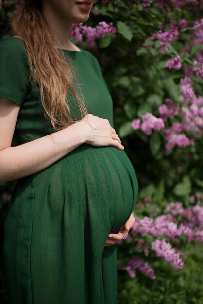 Nahaufnahme der schwangeren Frau umarmt ihren Bauch mit ihren Händen