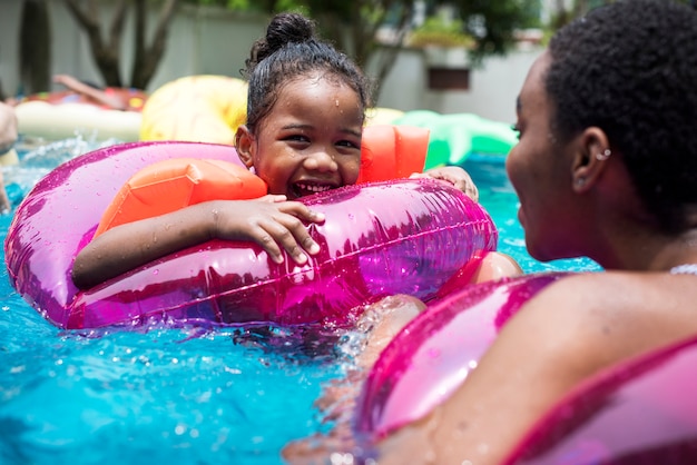 Nahaufnahme der schwarzen Mutter und der Tochter, die das Pool mit aufblasbaren Rohren genießt