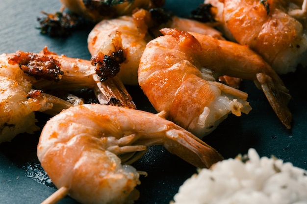 Nahaufnahme der schwarzen Schieferoberfläche mit köstlichen gebratenen Garnelen am Spieß