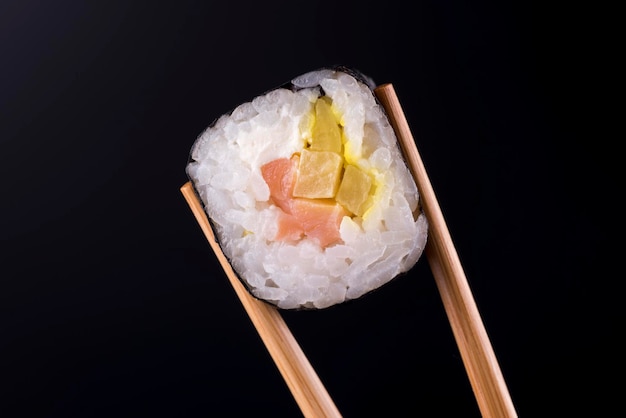 Nahaufnahme der Sushi-Rolle mit Lachs auf schwarzem Hintergrund