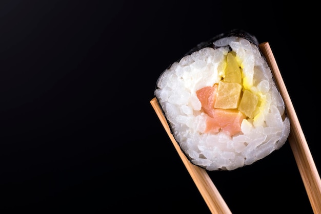 Nahaufnahme der Sushi-Rolle mit Lachs auf schwarzem Hintergrund