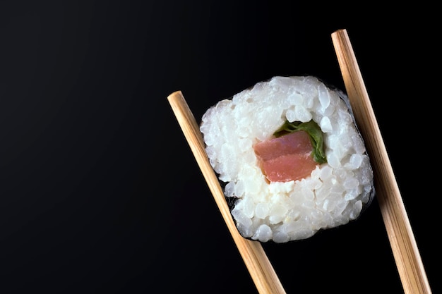 Nahaufnahme der Sushi-Rolle mit Lachs auf schwarzem Hintergrund