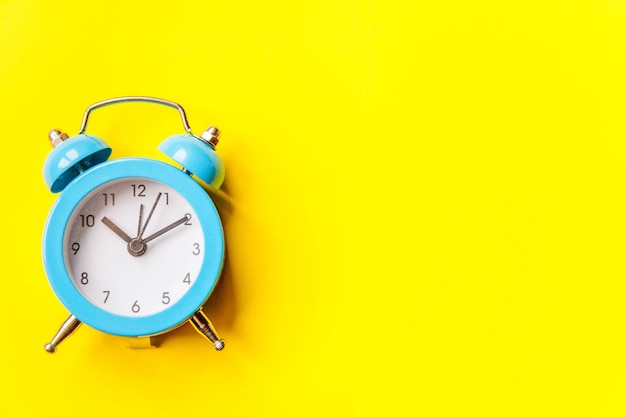 Nahaufnahme der Uhr auf dem Tisch gegen die gelbe Wand