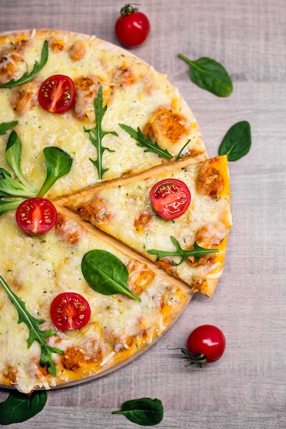 Nahaufnahme der vegetarischen Pizza mit Tomaten und Kräutern über Holztischhintergrund