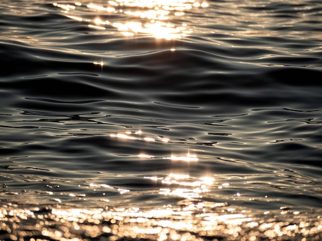 Nahaufnahme der Wasseroberfläche mit Sonnenschein bei Sonnenuntergang am Abend