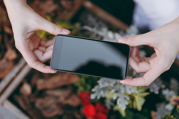 Nahaufnahme der weiblichen Hände machen ein Foto auf dem Handy mit leerem, leerem Bildschirm