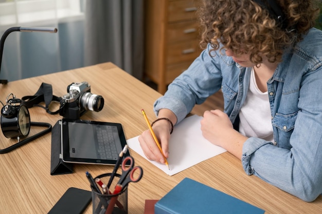 Nahaufnahme des amerikanischen Teenagers, der Notizen schreibt, studieren mit Laptop und Büchern, ernsthafter weißer Mann High School