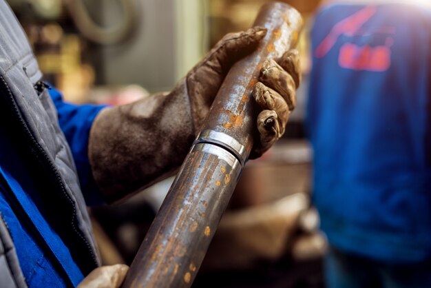 Nahaufnahme des Arbeiters in der Schutzuniform, die zwei Metall hält