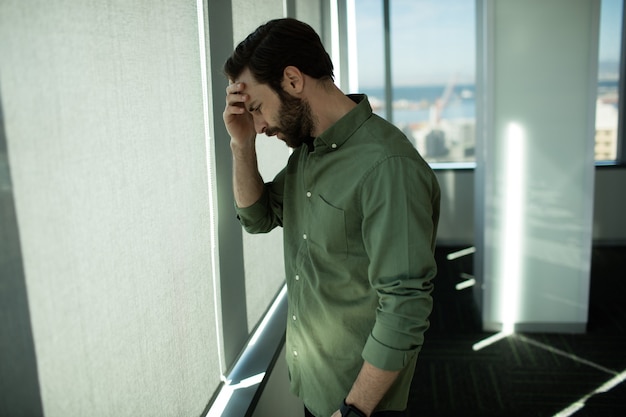 Nahaufnahme des besorgten Geschäftsführers, der durch Fenster im Büro steht