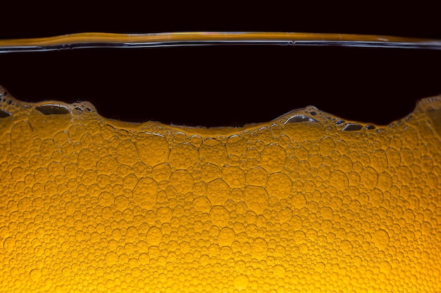 Nahaufnahme des bieres nahaufnahme in schaum und bierblasen auf schwarzem hintergrund wassertropfen hintergrund