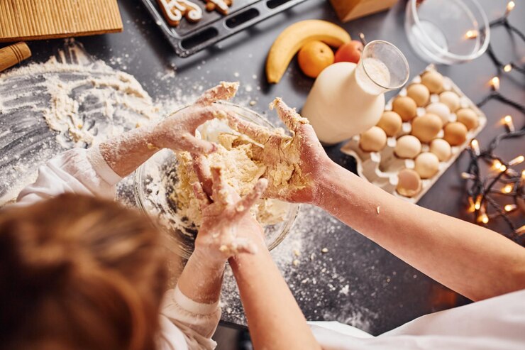 Foto nahaufnahme des bruders mit seiner kleinen schwester, die essen in der küche zubereiten und spaß haben.