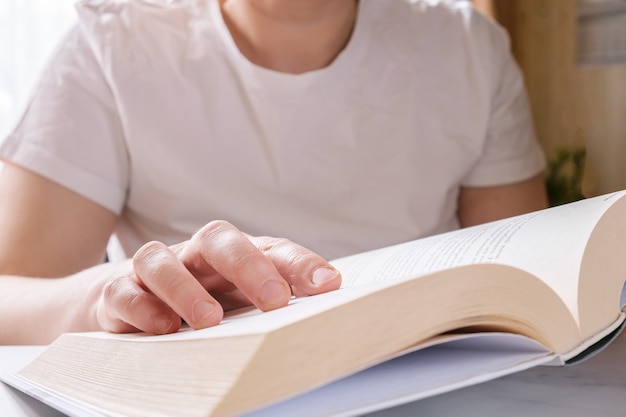 Nahaufnahme des geöffneten dicken Papierbuches in den Händen der Frau.