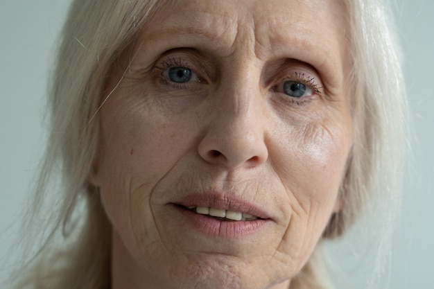 Nahaufnahme des Gesichts einer älteren Frau mit grauen Haaren, die in die Kamera schaut