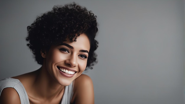 Nahaufnahme des Gesichts einer jungen Frau mit einem wunderschönen Lächeln, isoliert auf einer grauen Wand mit Kopierplatz, erfolgreiches multiethnisches Mädchen, Frau, die sich gegen eine graue Wand mit einem großen, zähneweißenden Lächeln in die Kamera schaut