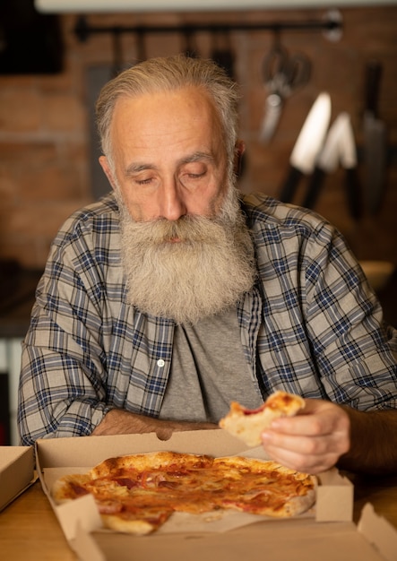 Nahaufnahme des glücklichen bärtigen älteren Mannes, der Pizza isst