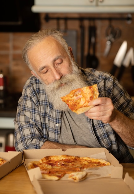 Nahaufnahme des glücklichen bärtigen älteren Mannes, der Pizza isst