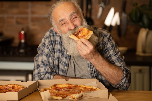 Nahaufnahme des glücklichen bärtigen älteren Mannes, der Pizza isst