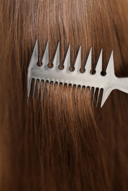 Nahaufnahme des Haarpflegekamms bewegt sich entlang einer schönen, gesunden, langen, fließenden braunen Haarstruktur, gesund