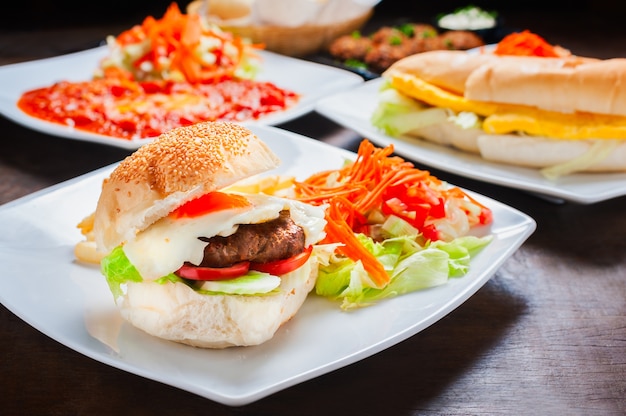 Nahaufnahme des Hamburgers mit Rindfleisch, Spiegelei, Gurke, Kopfsalat mit anderer israelischer Nahrung