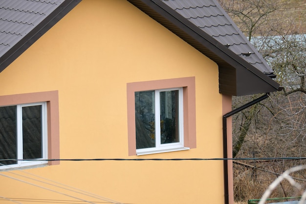 Nahaufnahme des Hausdaches, das mit metallischen Schindeln bedeckt istFliesenabdeckung des Gebäudes