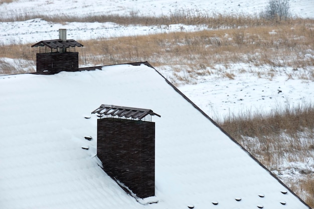 Nahaufnahme des Hausdachs, das im kalten Winter mit Schnee bedeckt ist Gekachelte Abdeckung des Gebäudes im Winterwetter