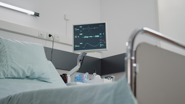 Nahaufnahme des Herzfrequenzmonitors für die Puls- und Gesundheitsuntersuchung in einer leeren Krankenstation. Niemand im Reanimationsraum mit Instrumenten und Werkzeugen zur Intensivpflege und Heilung.