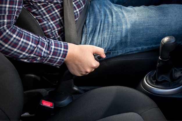 Nahaufnahme des jungen Mannes, der Handbremshebel im Auto zieht