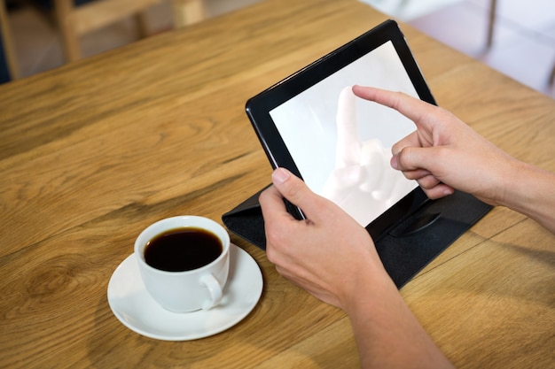 Nahaufnahme des jungen Mannes unter Verwendung der digitalen Tablette mit leerem Bildschirm im Kaffeehaus