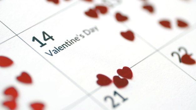 Nahaufnahme des Kalenderblattes mit dem Datum des 14. Februar mit schönen roten Papierherzen Valentinstag