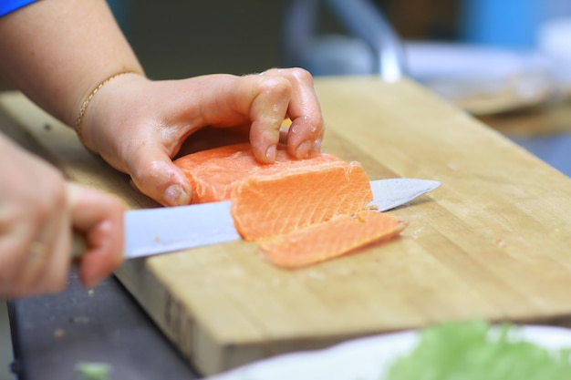 Nahaufnahme des Kochs, der Fisch für Sushi schneidet