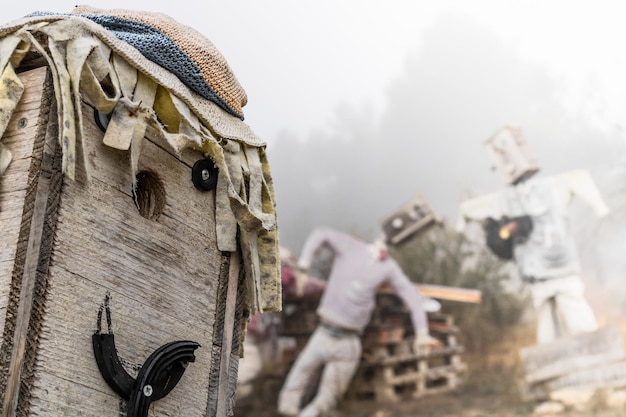 Nahaufnahme des Kopfes einer Vogelscheuche aus Holz mit einigen anderen Vogelscheuchen im Hintergrund des Bildes