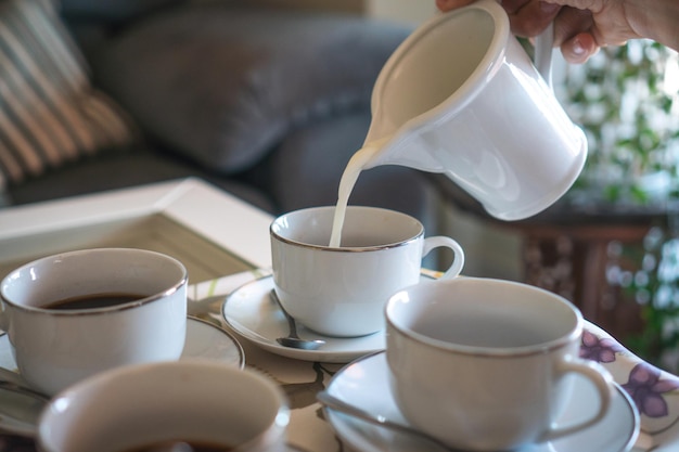 Nahaufnahme des Krugs, der Milch in Kaffees gießt