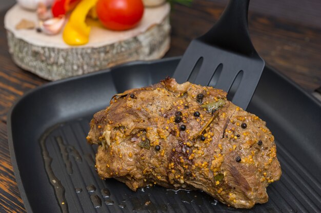 Nahaufnahme des Küchenspatels verteilt vorbereitetes Fleisch auf einer Grillpfanne neben Gemüse