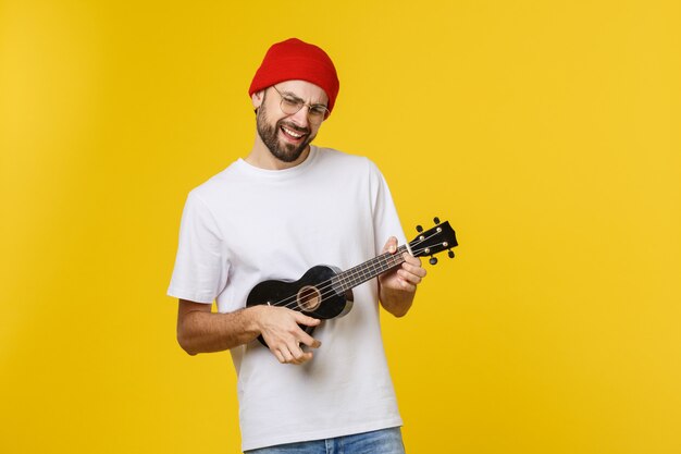 Nahaufnahme des lustigen jungen Mannes, der eine Gitarre spielt. isoliert auf gelbgold