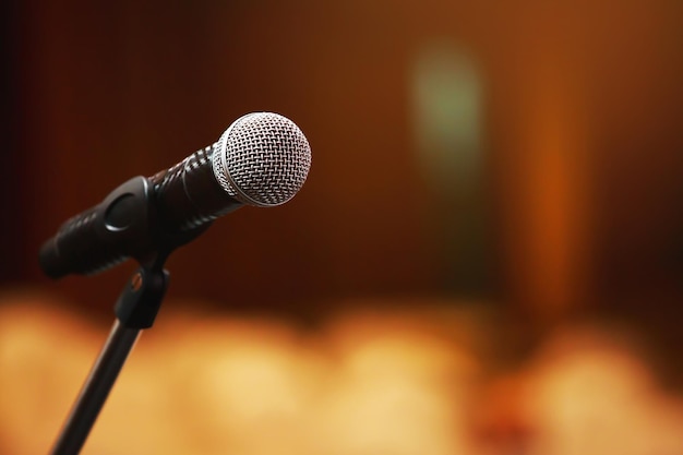 Nahaufnahme des Mikrofons auf der Bühnenbeleuchtung im Konzertsaal oder Konferenzraum. Raumbanner kopieren. Weicher Fokus.