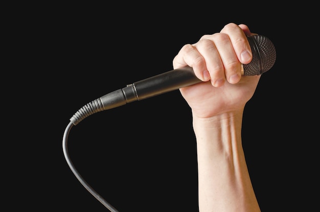 Nahaufnahme des Mikrofons in der Hand lokalisiert auf einem schwarzen Hintergrund