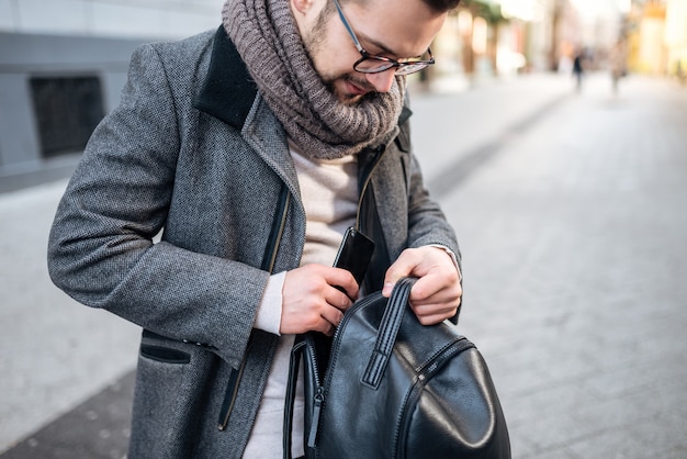 Nahaufnahme des modischen jungen Mannes mit Rucksack in der Stadt.