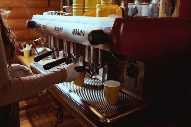 Nahaufnahme des nicht erkennbaren Barista, der Kaffee in der professionellen Kaffeemaschine macht