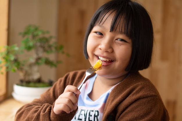 Nahaufnahme des Porträts der jungen Asiatin, die kleine Früchte mit einer Gabel isst