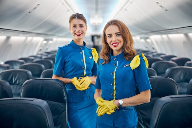 Nahaufnahme des Porträts des schönen Flugzeugpersonalteams in blauer Uniform, das auf dem Board des Verkehrsflugzeugs steht