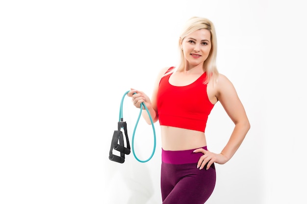 Nahaufnahme des Porträts einer selbstbewussten jungen Fitnessfrau, die Übungen mit Handexpander auf grauem Hintergrund macht
