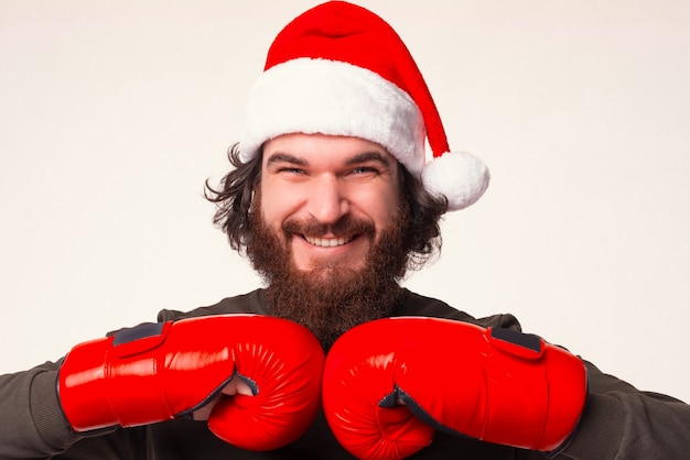 Foto nahaufnahme des porträts eines bärtigen mannes, der die hände in boxhandschuhen zusammenlegt.