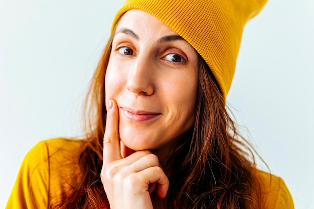 Nahaufnahme des Porträts eines Hipster-Gir-Teenagermädchens mit dem Finger im Mund und gelbem Hut auf dem Kopf