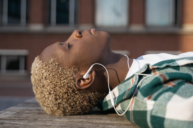 Nahaufnahme des Porträts eines stilvollen afroamerikanischen Mannes, der sich entspannt und mit geschlossenen Augen Musik hört