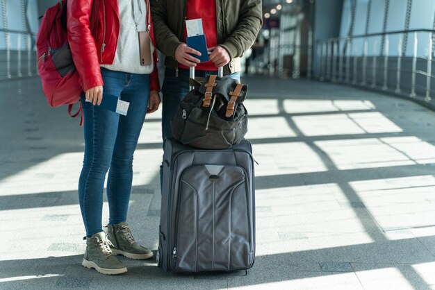 Nahaufnahme des Reisepaares, das sich beim Tragen von Gepäck aneinander bindet und vor seiner Reise in der Flughafenhalle steht. Stock Foto