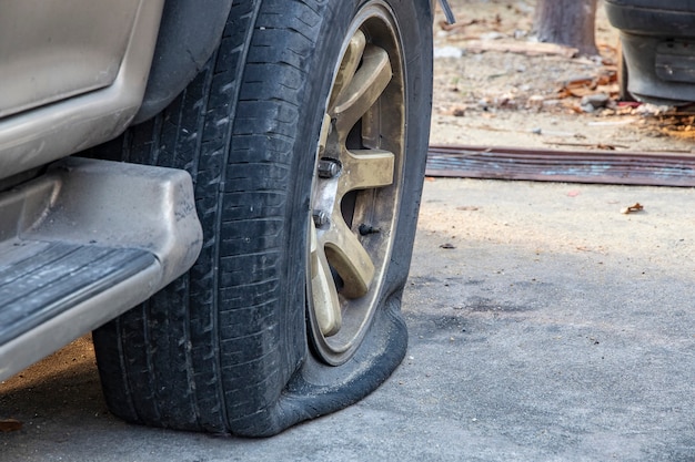 Nahaufnahme des schädigenden platten Reifens des Autos auf Parken.