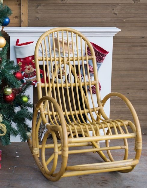 Nahaufnahme des Schaukelstuhls neben dem Kamin mit Socken für Geschenke und Weihnachtsbaum