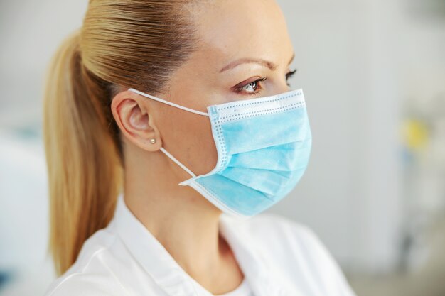 Nahaufnahme des schönen Laborassistenten mit schützender steriler Gesichtsmaske auf. Covid 19-Ausbruchskonzept.