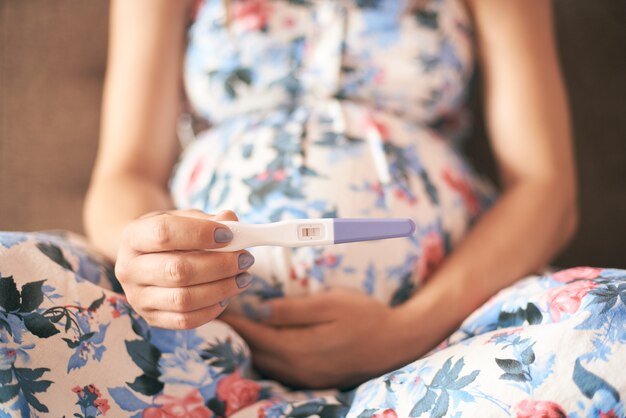 Nahaufnahme des Schwangerschaftstests in den Händen der jungen Frau